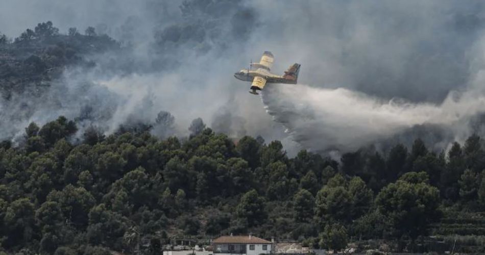 Avión de extinción descarga agua sobre un incendio forestal que afecta zonas de Madrid, Ávila y Toledo, en España.