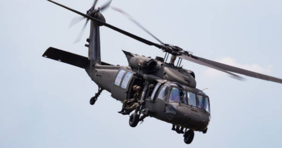Helicóptero Black Hawk del Ejército Nacional con militares visibles en la puerta lateral durante el vuelo.