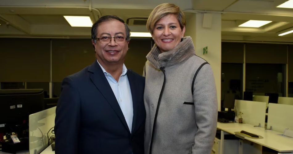 Gustavo Petro y Verónica Alcocer sonríen juntos en una oficina con puestos de trabajo.