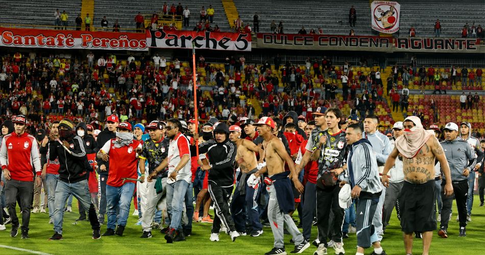 Hinchas de América y Santa Fe caminan por el campo de juego durante los disturbios en El Campín.