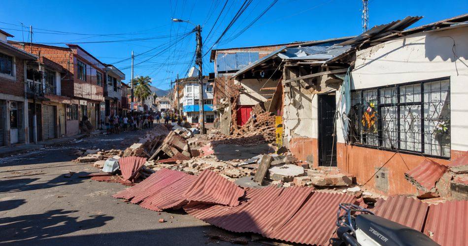 Calle de Sevilla con viviendas afectadas, escombros y estructuras deterioradas por el terremoto.