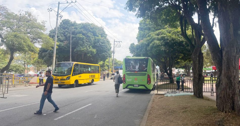 Bus alimentador de Megabús circula por una vía junto a otro vehículo de transporte público.