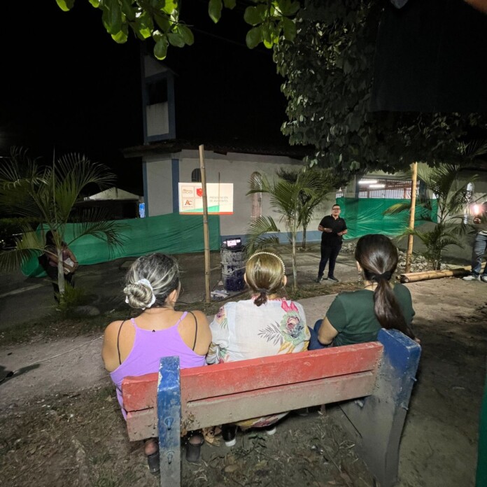 Obras en Torre La Vega comunidad reunida en un parque durante una actividad nocturna.