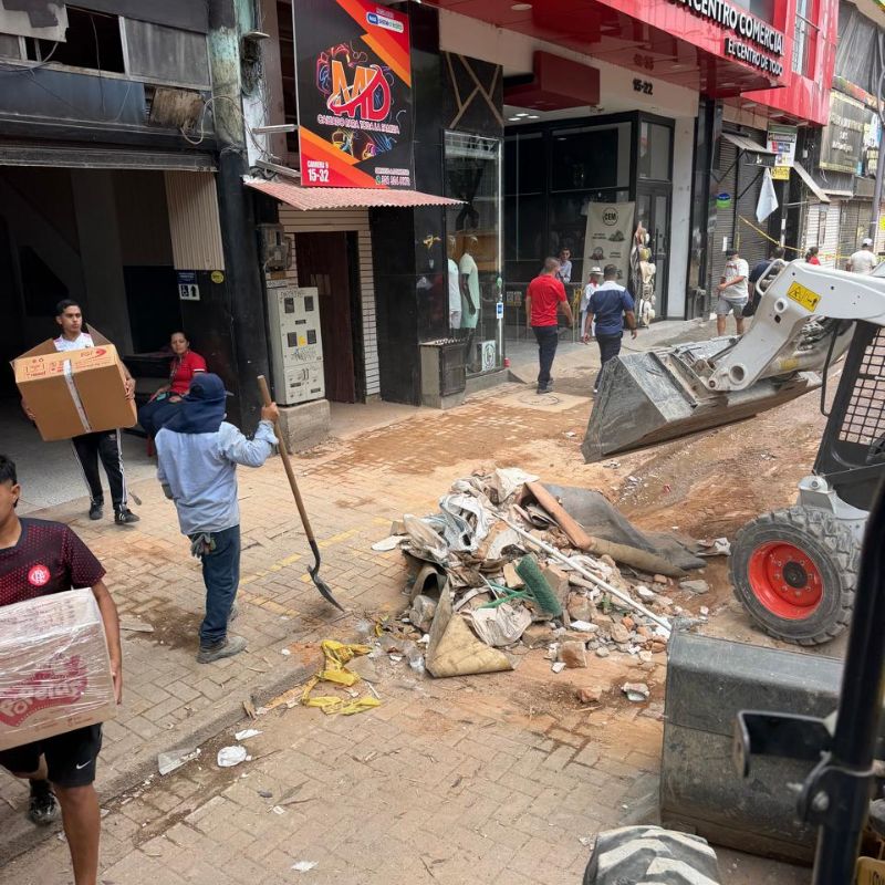 Recolección de escombros en Pereira con retroexcavadora y trabajadores realizando labores de limpieza en la Carrera Octava.
