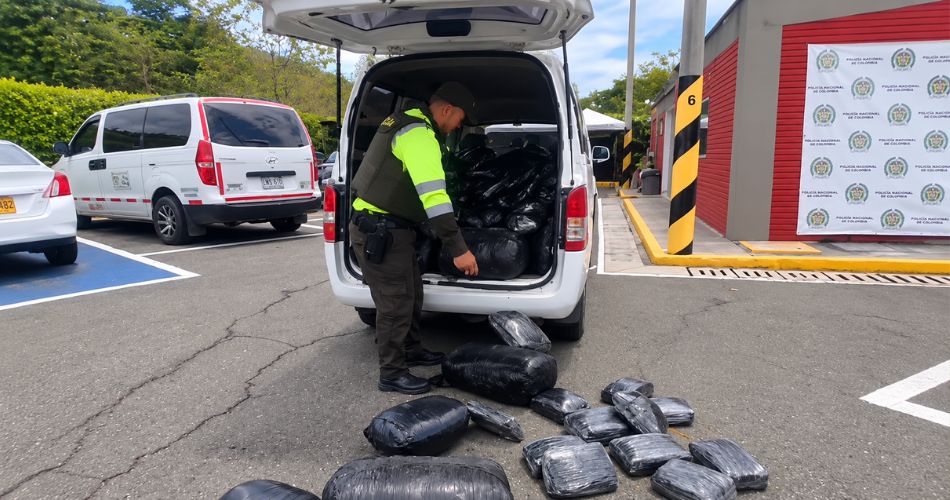 Policía inspecciona paquetes encontrados en la van interceptada durante el procedimiento.