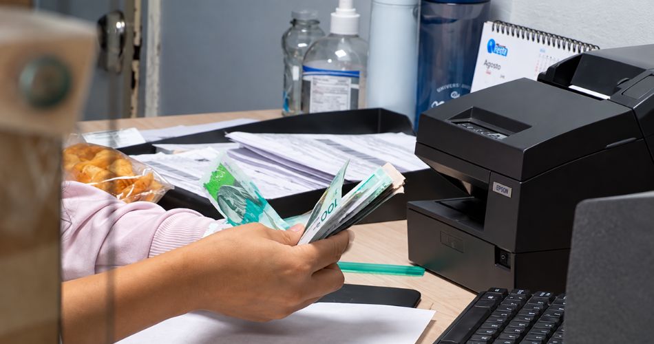 Persona cuenta dinero durante un proceso de pago relacionado con obligaciones tributarias.