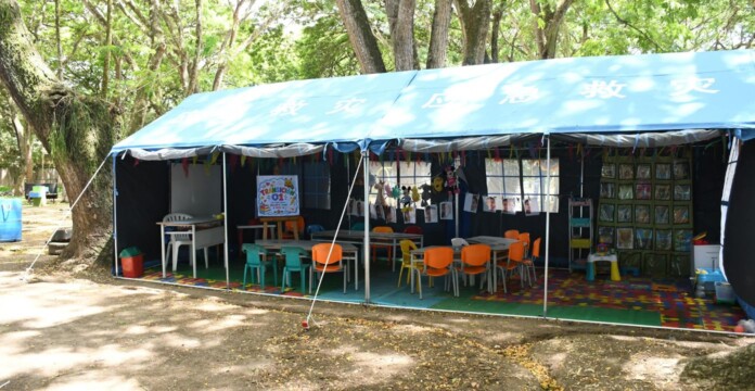 Estudiantes volvieron a clases en un albergue escolar acondicionado con mesas y sillas bajo una carpa
